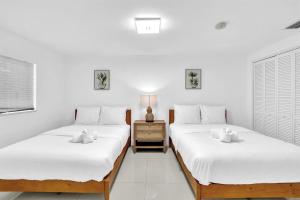 two beds in a room with white walls at 4BR Home Heated Pool And BBQ short drive Beach! in Hollywood +27 photos