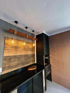 een keuken met een zwart aanrecht en wat verlichting bij cantinho da padroeira in Aparecida +2 foto's