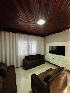 een woonkamer met een bank en een flatscreen-tv bij cantinho da padroeira in Aparecida