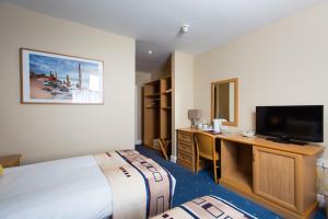 a hotel room with a bed and a desk and a television at Mercure Newbury West Grange Hotel in Thatcham