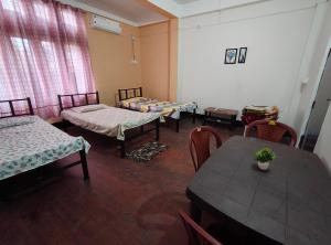 a room with several beds and a table and chairs at Nirmali Homestay in Guwahati +3 photos