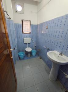 a blue and white bathroom with a toilet and a sink at Nirmali Homestay in Guwahati