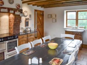 a kitchen with a wooden table with chairs and a counter at Buddileigh Farm in Betley