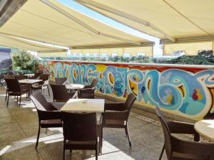 Hotel Excelsior Magenta في ماجنتي: مطعم به طاولات وكراسي وجدار ملون