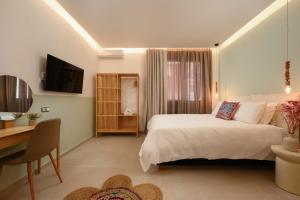 a bedroom with a bed and a desk and a television at Aurelia Suites in Benitses