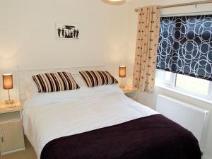 a bedroom with a white bed with two lamps and a window at Rosewater Lodge in Saint Teath