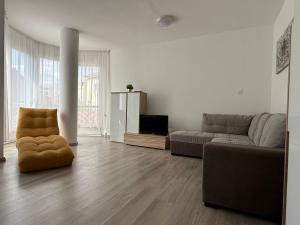 ein Wohnzimmer mit einer Couch und einem Sessel in der Unterkunft F25 Apartman in Pécs