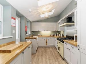 a large kitchen with white cabinets and wooden floors at Frankland House in Whitby