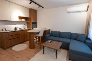 a living room with a blue couch and a kitchen at Modern Bazaar Apartment in Gjakove