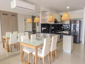 a kitchen with a dining table and white chairs at Bocagrande Infinitum Vista mar Gym Coworking in Cartagena de Indias