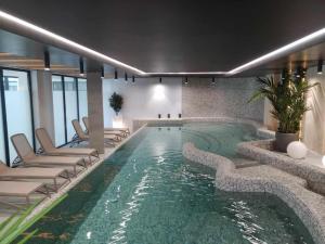 een groot zwembad met ligstoelen en een hotelkamer bij Baltic Waves Resort A323 in Międzyzdroje