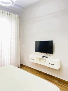 een slaapkamer met een flatscreen-tv aan een witte muur bij A&E Seaside Apartment in Golem