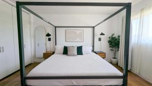 a bedroom with a canopy bed with white sheets and pillows at LA Huge Mid Century Guesthouse Patio LAX Beach in Los Angeles