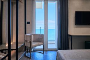 a hotel room with a chair in front of a window at THALORA - Luxury Apartments in Bari