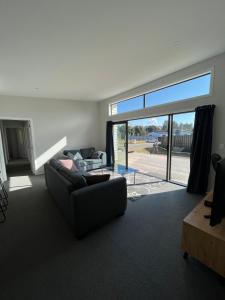 a living room with a couch and a large sliding glass door at Exclusive Holiday Home Sunny Beach House Four Queen Beds in Napier