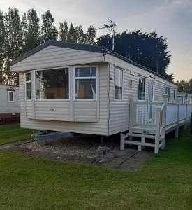 a white mobile home with a porch and a bench at Happy Days Chapel st Leonard's The Ocean Pearle in Chapel Saint Leonards