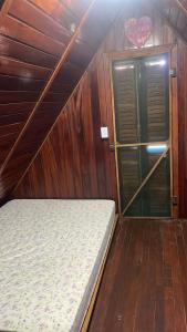 uma cama em um quarto com paredes de madeira e uma porta em Chalé Mississippi - Camping Carrion - ITU em Itu