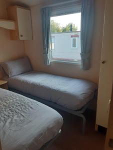a small bedroom with two beds and a window at Happy Days Chapel st Leonard's The Ocean Pearle in Chapel Saint Leonards