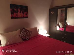 a bedroom with a bed with red sheets and a mirror at Villa Mimis in Agios Andreas