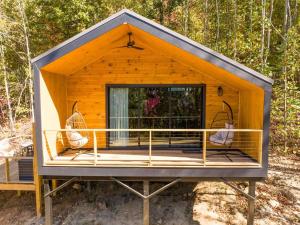 a tiny house with a porch in the woods at Blooming Redbud Treehouse with private hot tub in Wildwood