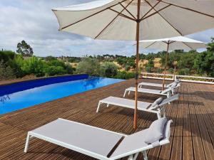 a patio with two chairs and an umbrella next to a pool at The Blue House Valley in Grândola