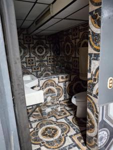 Un baño con inodoro y una pared de mosaico. en Alquileres El Ángel, en San Salvador 2 fotos más