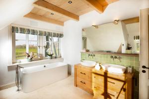a bathroom with two sinks and a tub and a mirror at Landhüüs Oeverdiek - Luxus am Golfplatz in Timmendorfer Strand