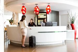 two women standing at a reception desk with a suitcase at Novotel Suites Marseille Centre Euromed in Marseille