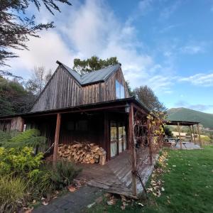a barn with a pile of logs on the porch at Okuti Retreat in Little River
