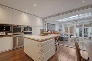 a kitchen with white cabinets and a living room at Stunning 4 Bedroom, 3 Bathroom House with Private Hottub & Gym - Escape London, in Lonon in London