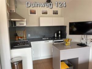 a kitchen with white cabinets and a counter top at Appartementen Zuiderstrand H in Westkapelle