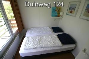 two beds in a small room with a window at Appartementen Zuiderstrand H in Westkapelle
