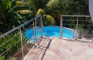 a blue swimming pool with a metal railing at VILLAS Lush Eden in Vieux-Habitants
