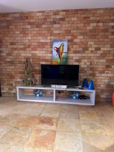 een wit entertainmentcentrum met een televisie aan een bakstenen muur bij SWEET HOME Águas Belas in Águas Belas
