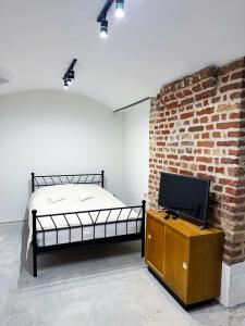 a bedroom with a bed and a tv and a brick wall at Wagners Refuge 3 in Rīga