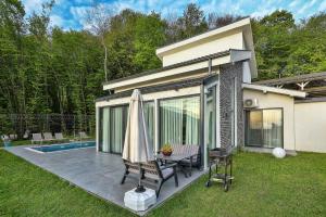un patio con una mesa y una sombrilla junto a una casa en New Balturk Nature Villas, en Sapanca