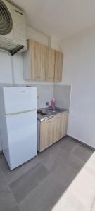 a kitchen with a white refrigerator and wooden cabinets at Apartments Daris in Ulcinj +26 photos