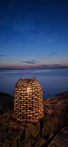 a lit up object sitting on the rocks near the water at Ithaca in Perdika