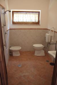 bagno con due servizi igienici, lavandino e finestra di Il Vallone di Melezzole a Melezzole