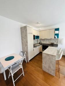 a kitchen with white cabinets and a table and chairs at Lazure apartment in Tivat