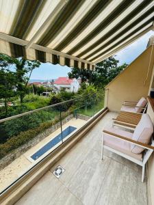 a balcony with two chairs and a large window at Lazure apartment in Tivat