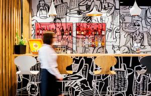 eine Person, die an einer Bar vorbeigeht, deren Wand mit Graffiti bedeckt ist in der Unterkunft Ibis Poznan Polnoc in Suchy Las