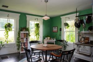 una sala da pranzo con tavolo, sedie e pareti verdi di Cozy Skiing Vacation in Historic 1800’s Colonial a Tinmouth
