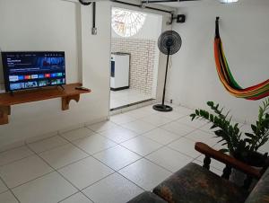 ein Wohnzimmer mit einem TV, einem Sofa und einem Ventilator in der Unterkunft Casa perto da praia em Mosqueiro-PA in Belém