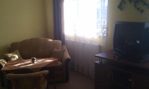 a living room with a tv and a chair and a table at Hotel Pod Dębami in Pabianice