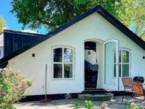ein kleines weißes Haus mit zwei Fenstern und einem Stuhl in der Unterkunft 4 person holiday home in Aabenraa-By Traum in Aabenraa