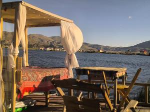 a table and chairs on a dock next to the water at Uros Quechua`s Lodge Titicaca in Puno