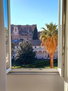 ein Blick auf eine Palme aus einem offenen Fenster in der Unterkunft Camera x2 con splendida vista sulle Terme di Diocleziano e sul Chiostro di Michelangelo in Rom