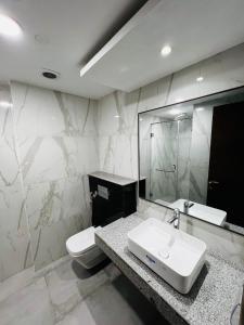 a bathroom with a sink and a toilet and a mirror at Prestige Suitess in Lahore