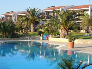 a large swimming pool with palm trees and houses at Helidonia in Loutra Killinis